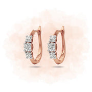 Rose gold hoop earrings with diamond accents on a light pink background