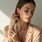 Woman wearing a necklace and earrings against a neutral background